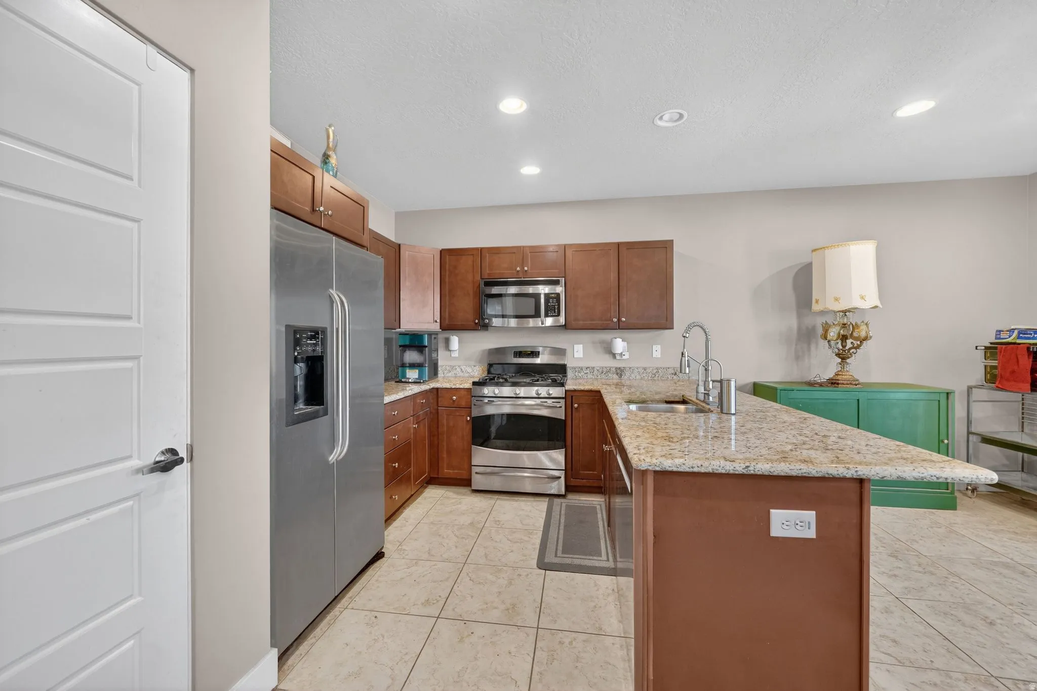 Kitchen featuring an L-shaped counter with a granite-style surface and an integrated sink