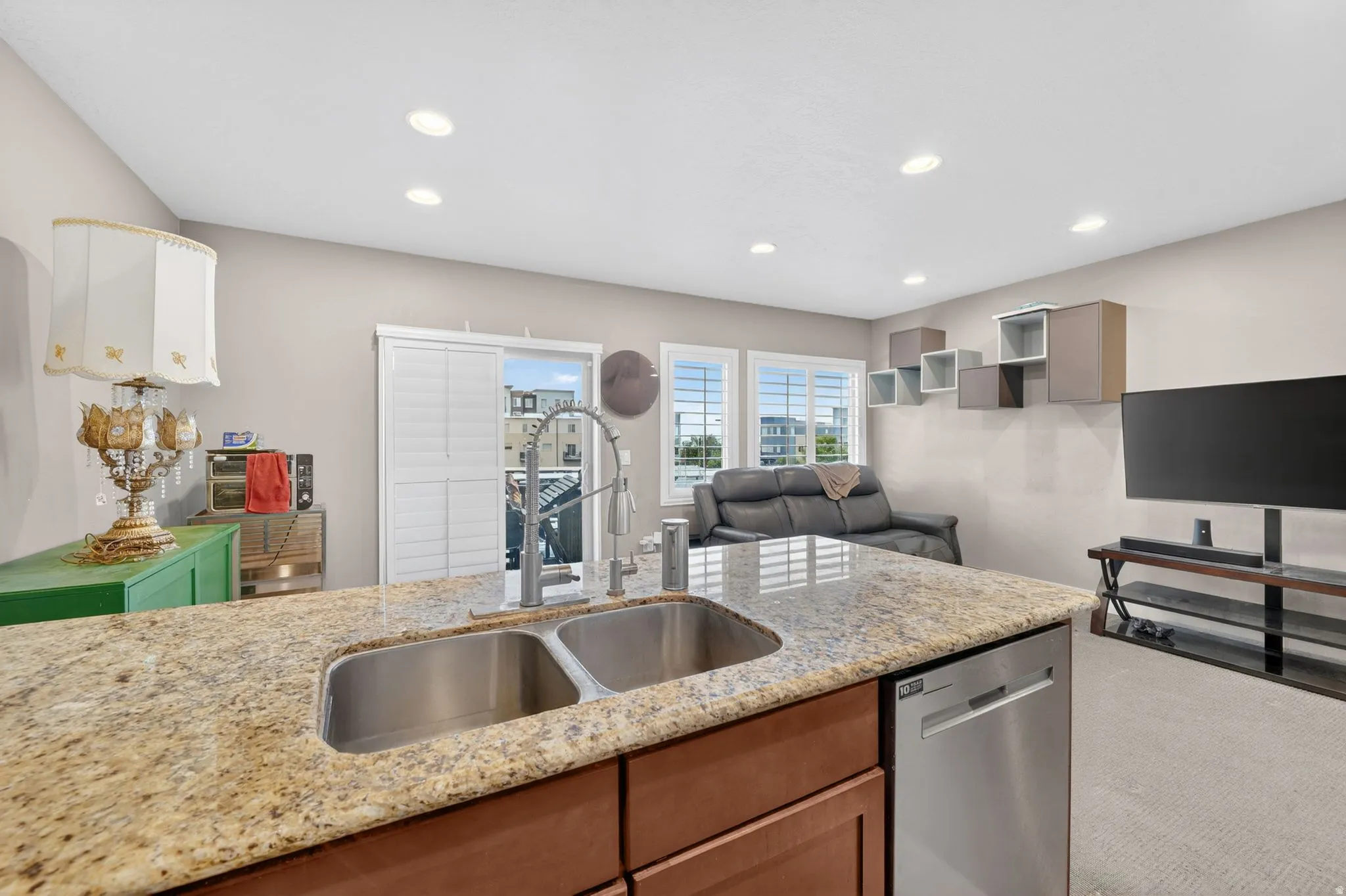 Kitchen island with granite countertop, double stainless steel sink, and stainless steel dishwasher
