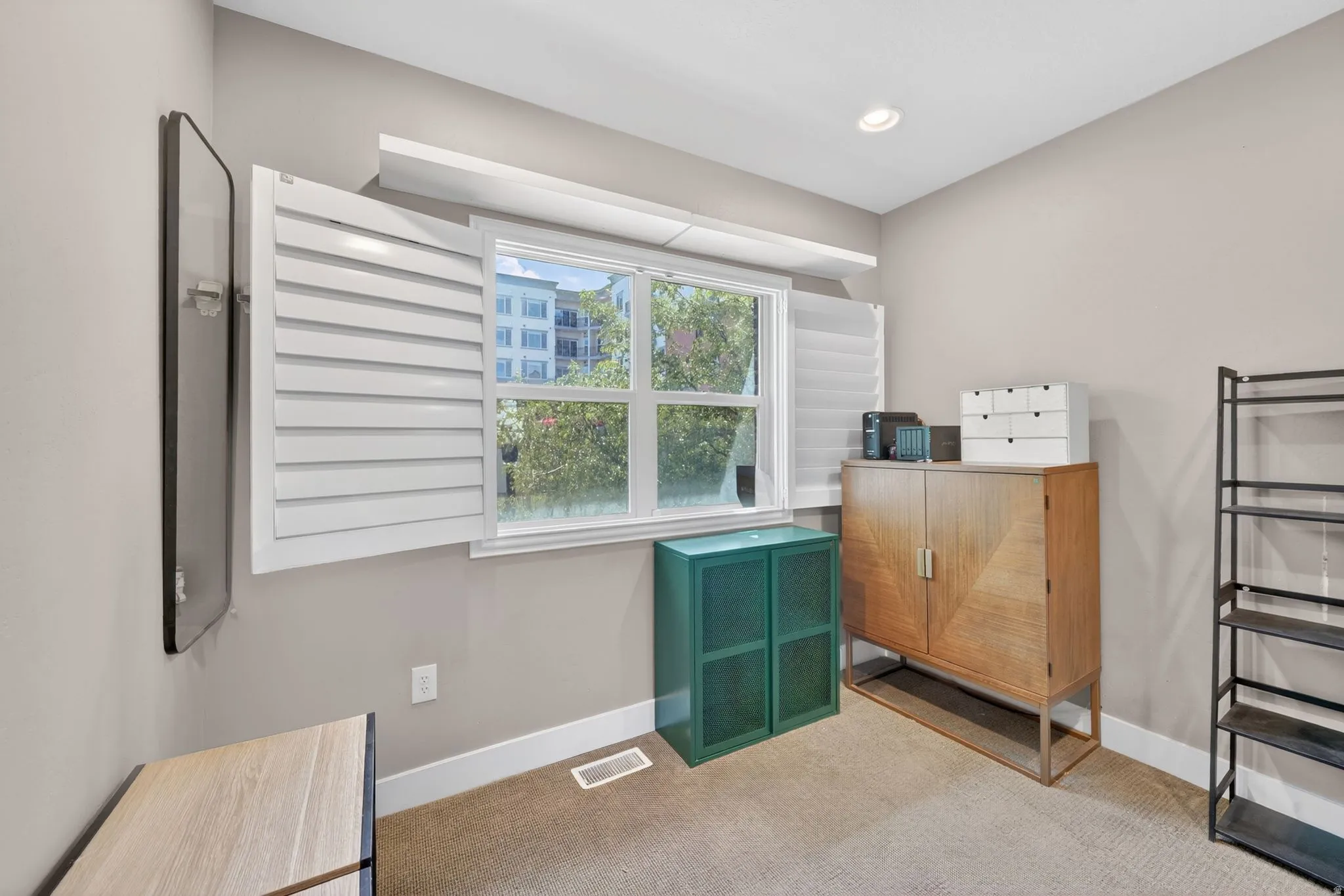 Window with white louvered shutters, recessed lighting, and neutral wall tones