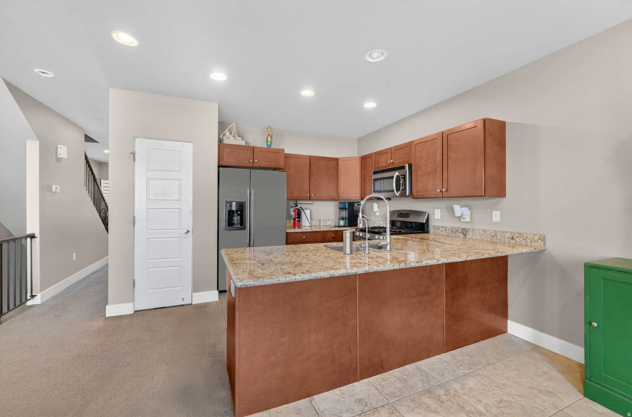 Kitchen featuring wood cabinetry, stainless steel appliances, and a granite-look island with an integrated sink