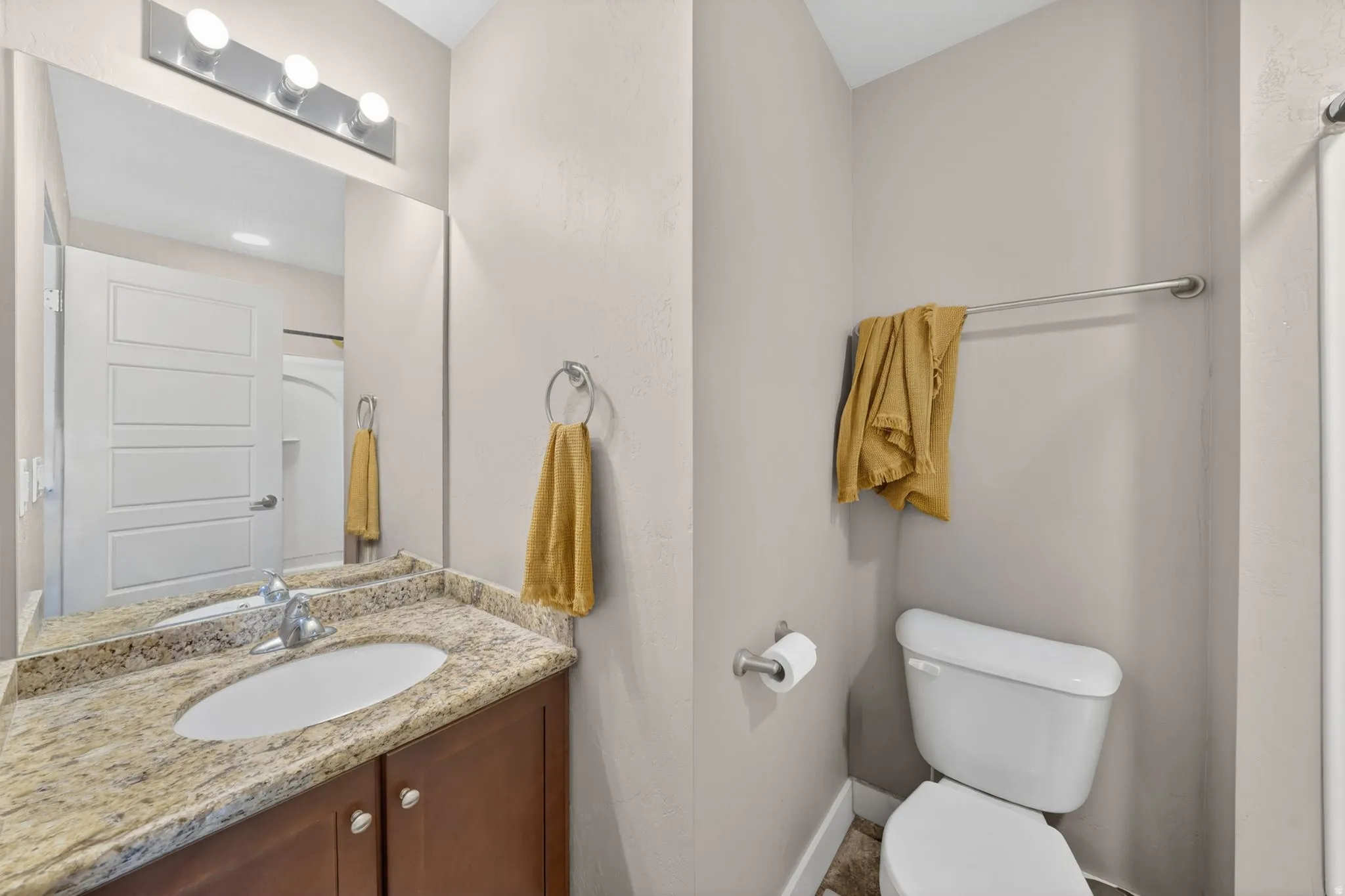 Vanity featuring a stone-finish countertop with an undermount sink and chrome faucet