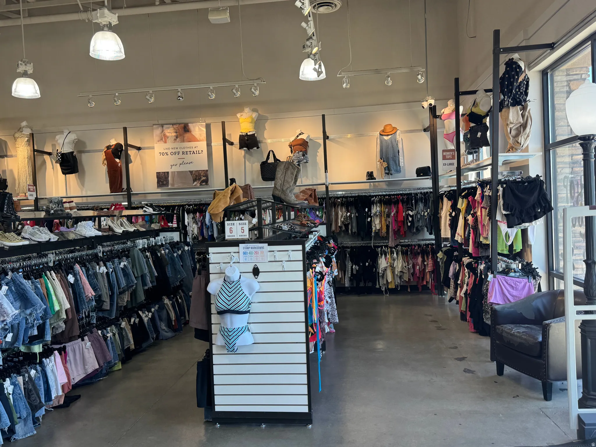Spacious retail interior featuring track lighting, exposed ceiling ductwork, and abundant merchandise racks