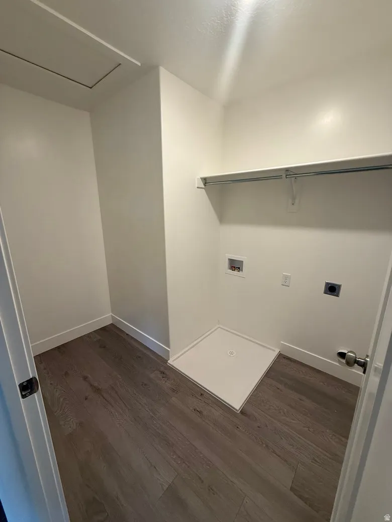 Dedicated laundry area featuring wood-finish flooring, white walls, and a built-in shelf with hanging rod