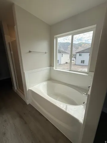 Soaking tub featuring a tiled surround and a window with mountain scenery