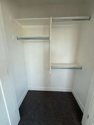 Interior closet featuring multiple white shelving units and chrome hanging rods