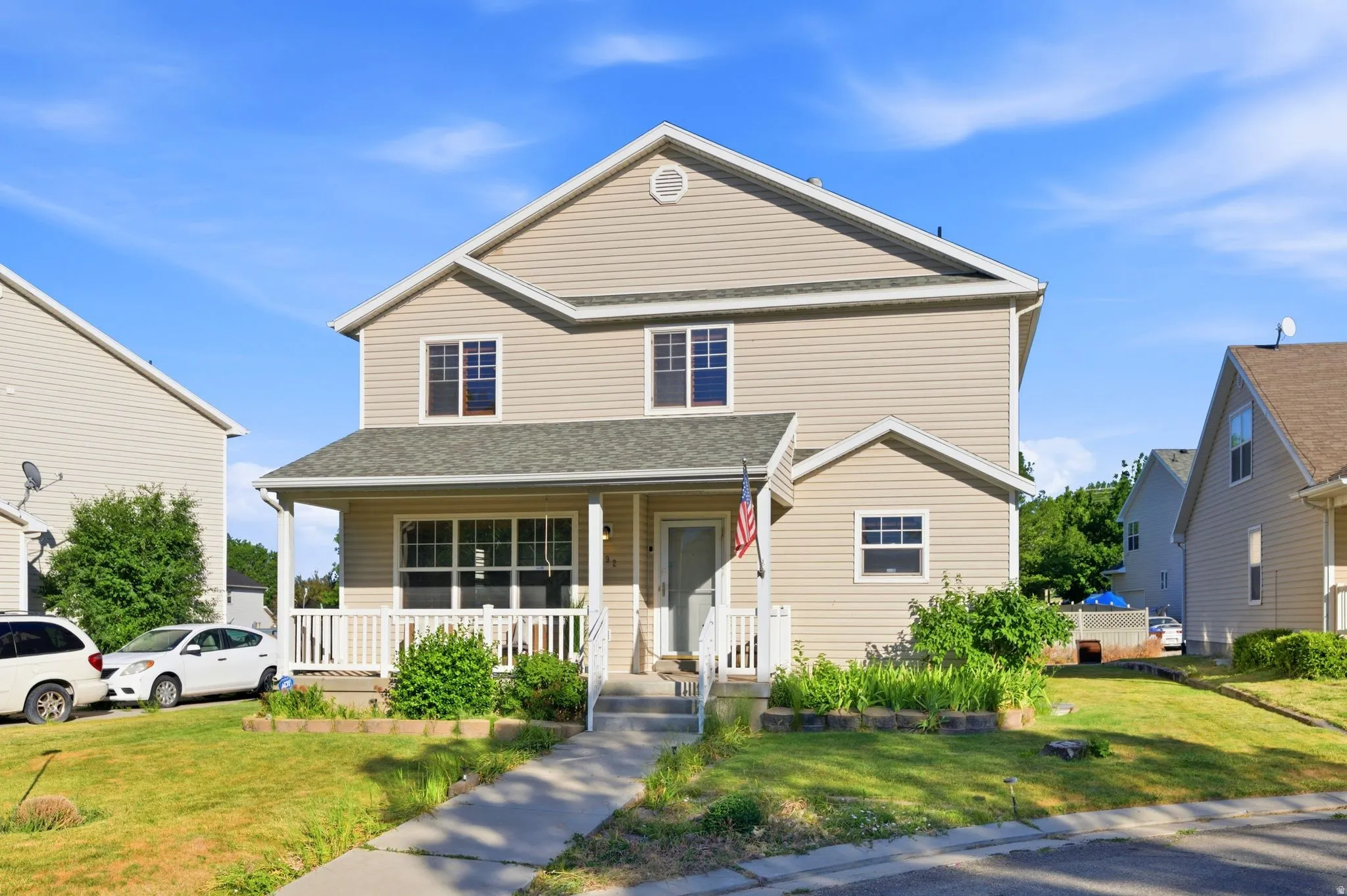 Two-story residence featuring light-colored siding, a covered front porch, and an attached garage