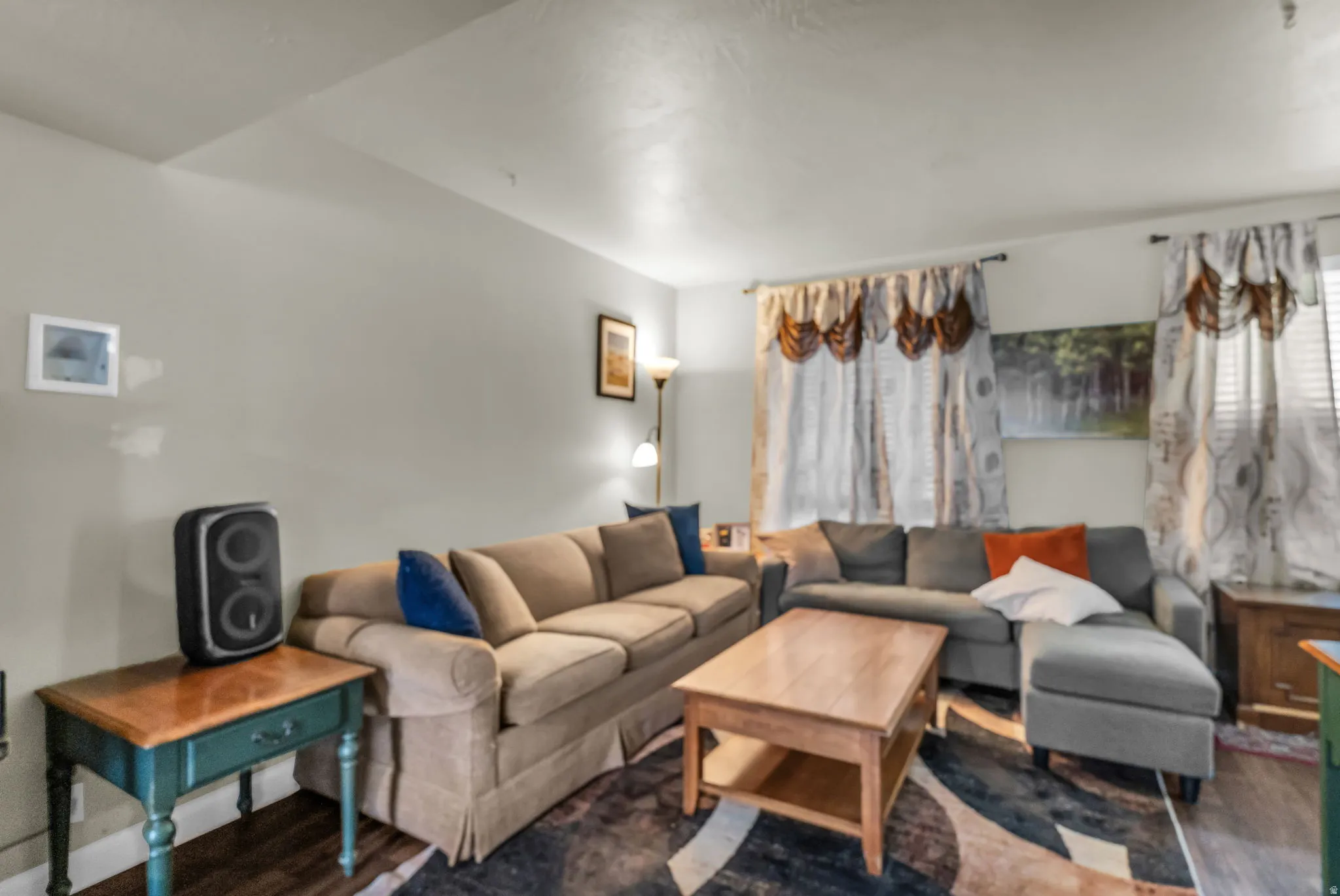 Spacious living area featuring light-toned wall paint and dark wood-finish flooring