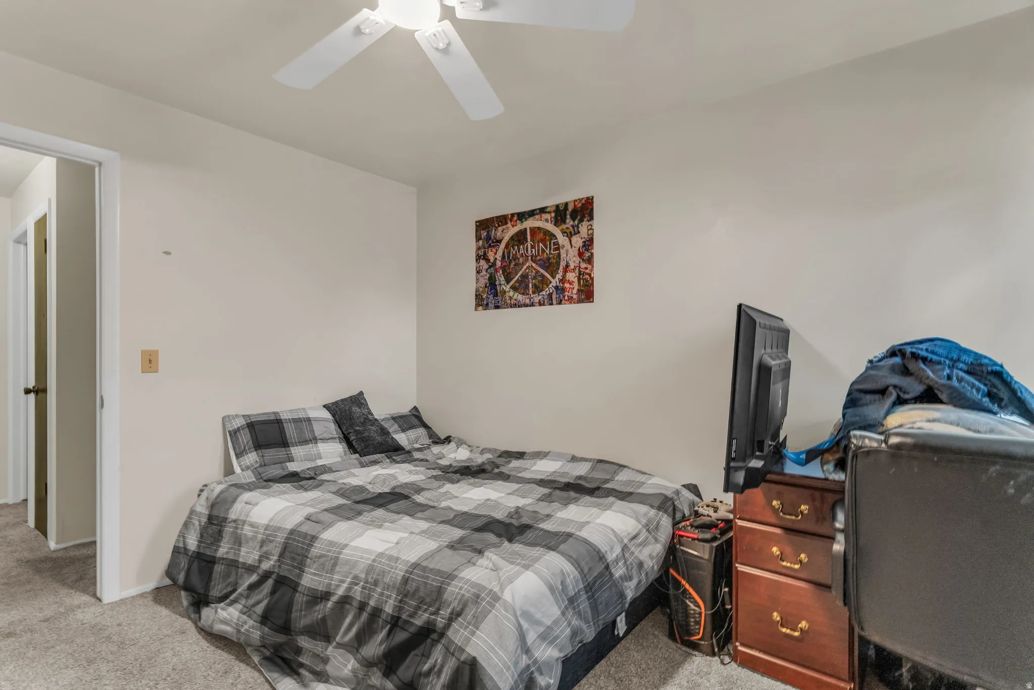 Neutral wall paint with gray carpeting, featuring a ceiling fan, and a doorway with a dark-paneled door