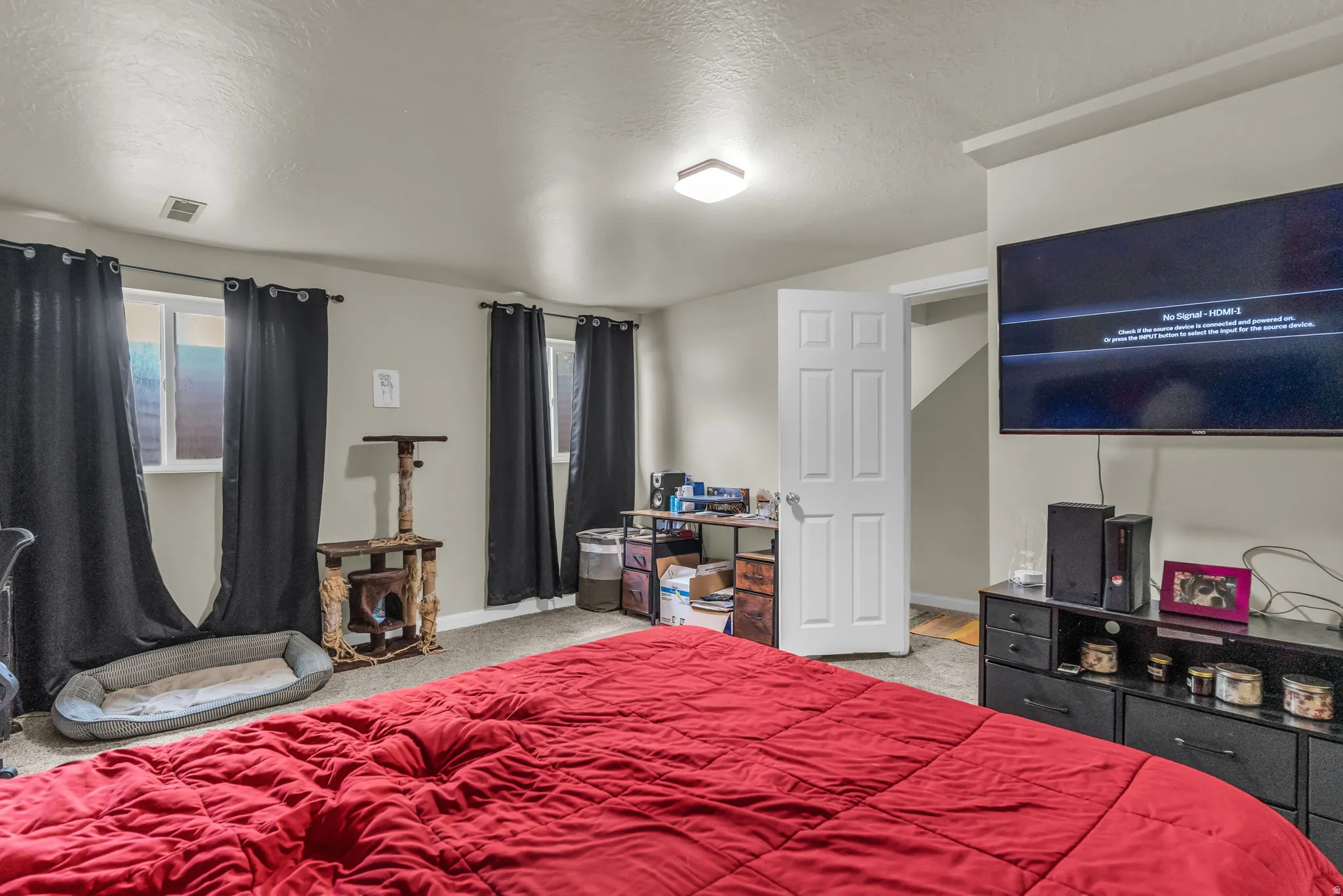 Carpeted room featuring multiple windows with dark curtains, a built-in wall niche, and an overhead flush-mount light fixture