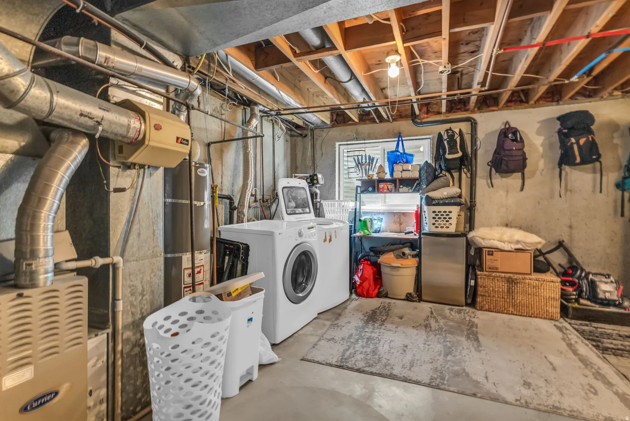 Unfinished basement area featuring exposed ceiling joists and concrete walls