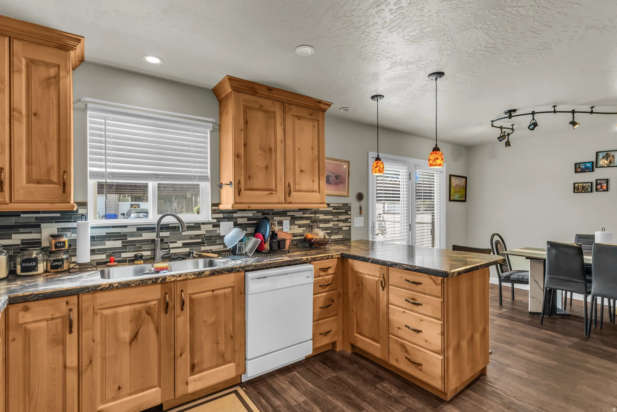 Kitchen featuring wood cabinetry, stone-look countertops, a mosaic tile backsplash, stainless steel sink, and wood-finish flooring