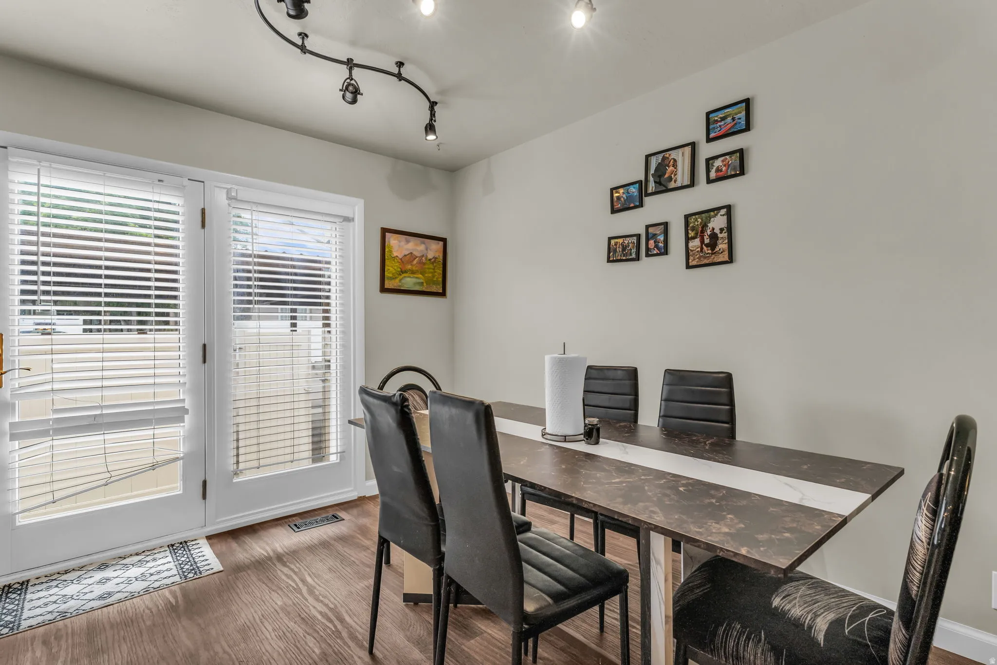 Dining area featuring wood-finish flooring, light grey walls, and a track lighting fixture