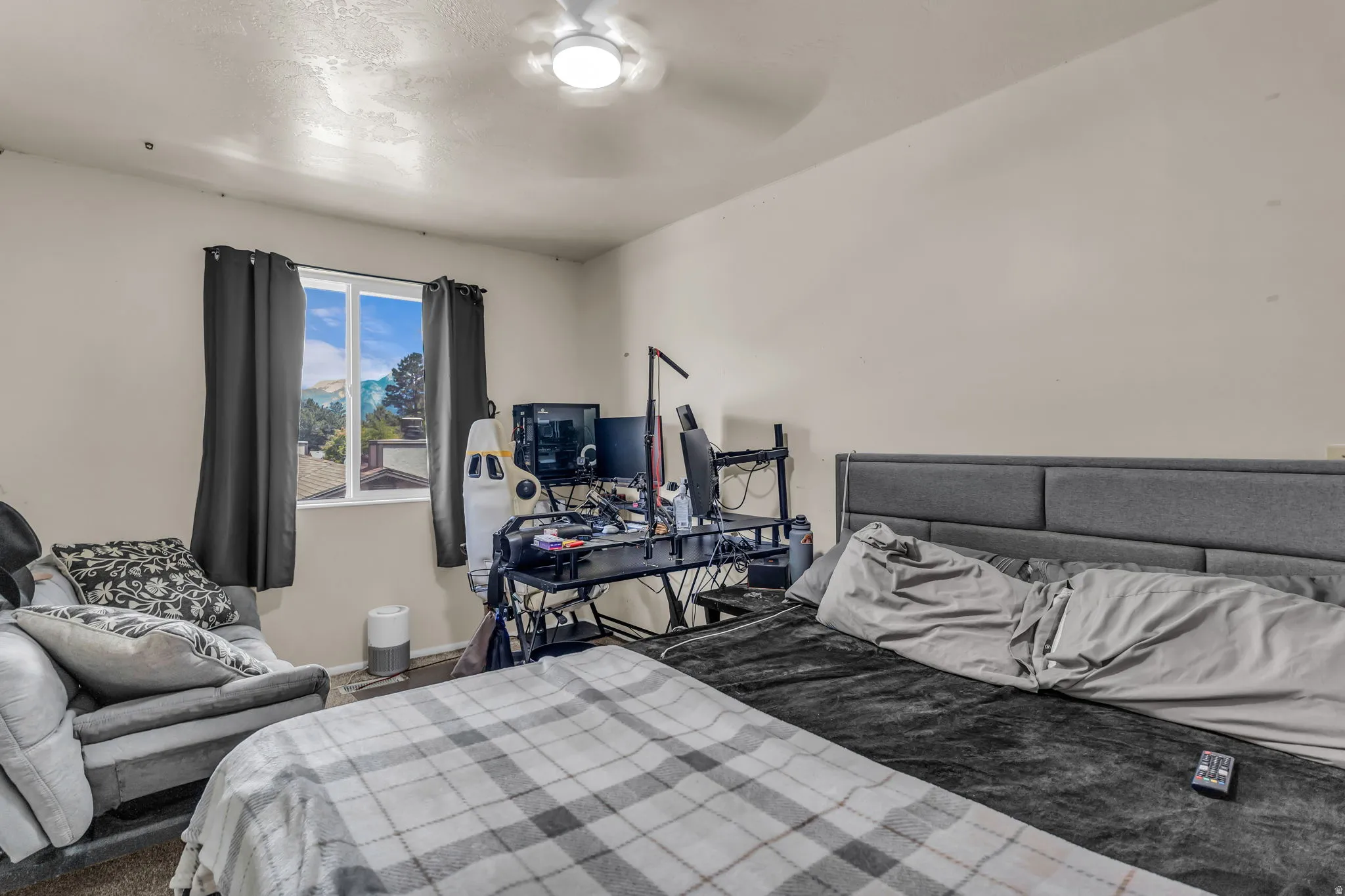 Bedroom featuring a white ceiling fan, single window with dark drapery, and neutral wall paint