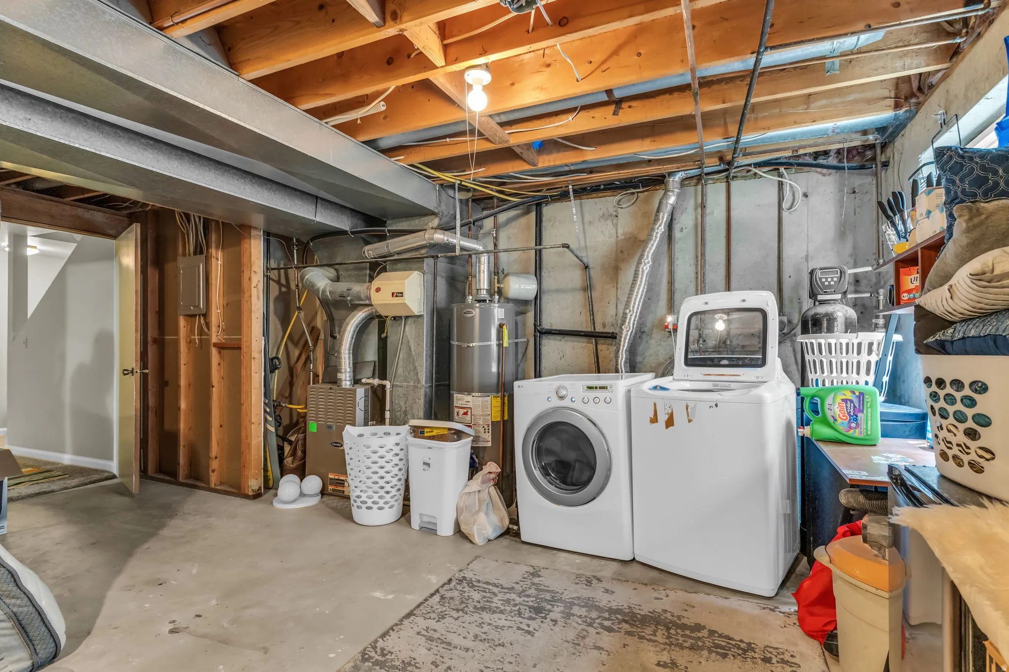 Basement utility area featuring a concrete floor, exposed wood ceiling joists, and a washer and dryer