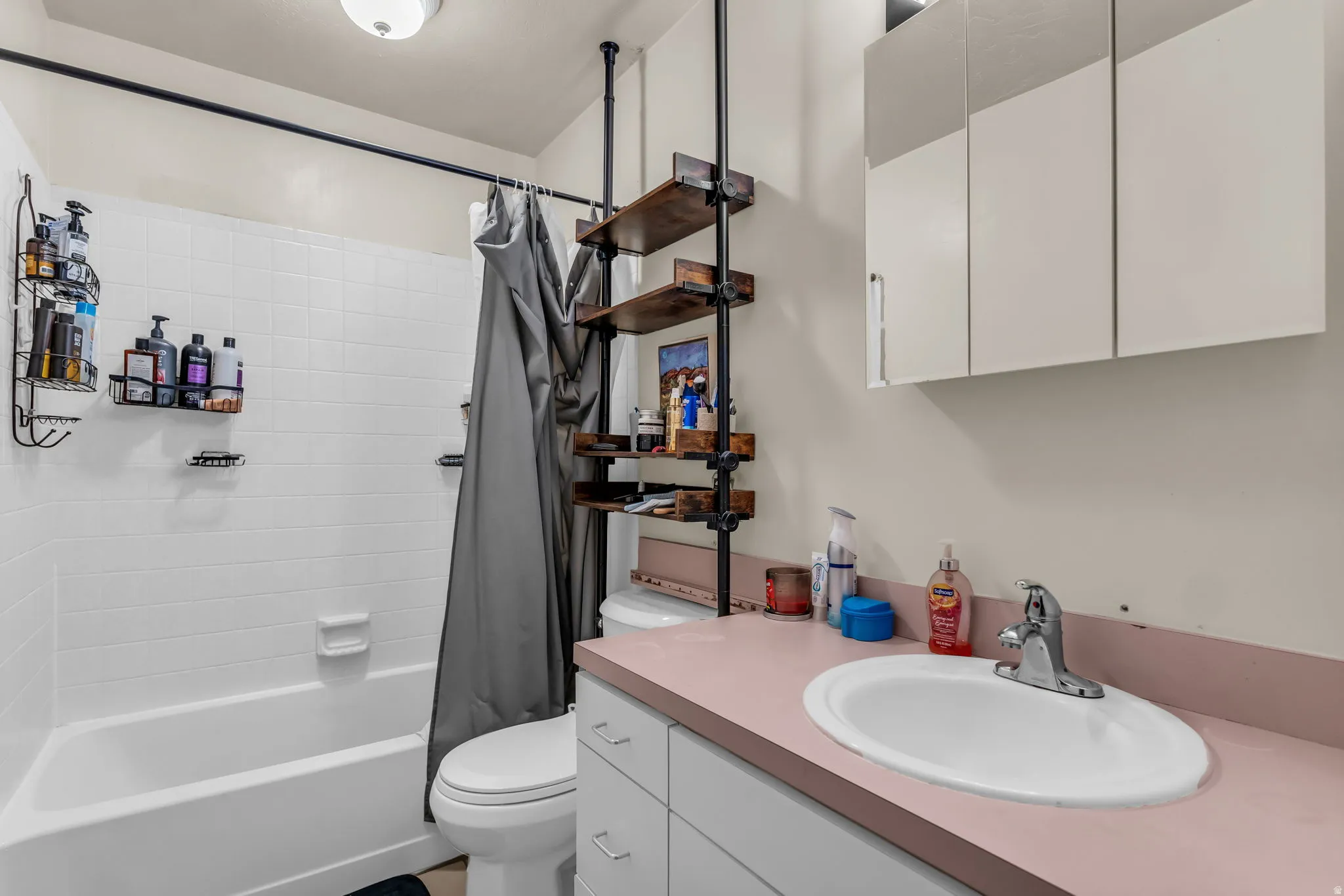 Bathroom featuring a white bathtub with subway tile surround, white toilet, and a vanity with a drop-in sink