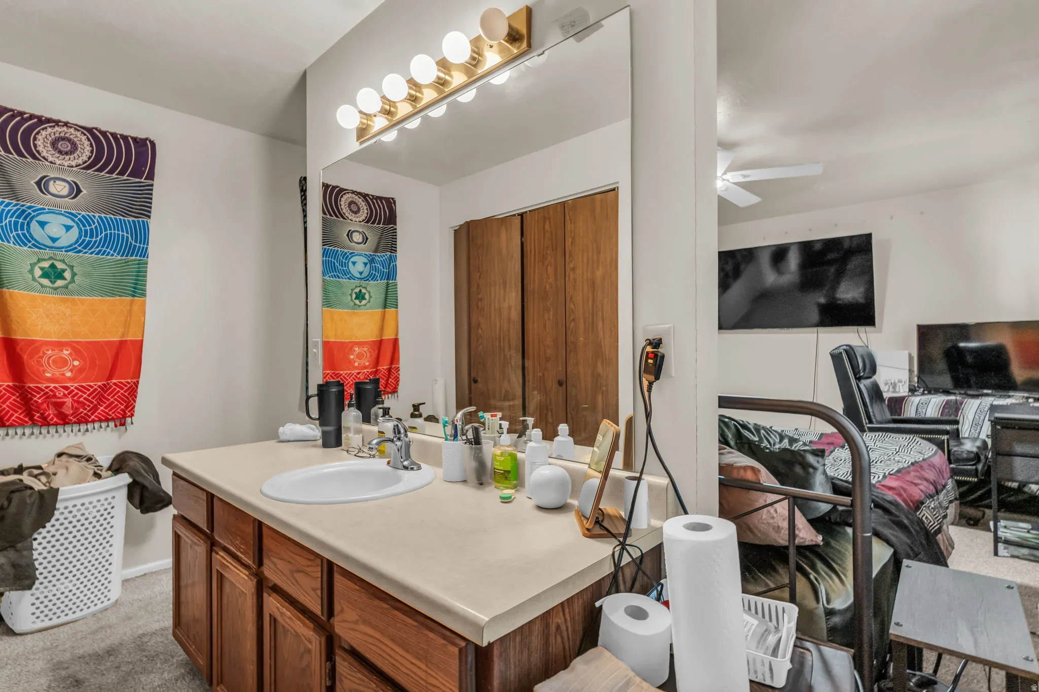 Vanity area featuring a single basin sink, laminate countertop, wood-finish cabinetry, and a full-width mirror with a five-bulb vanity light fixture