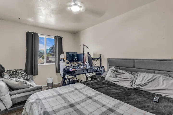 Bedroom featuring a white ceiling fan, single window with dark drapery, and neutral wall paint