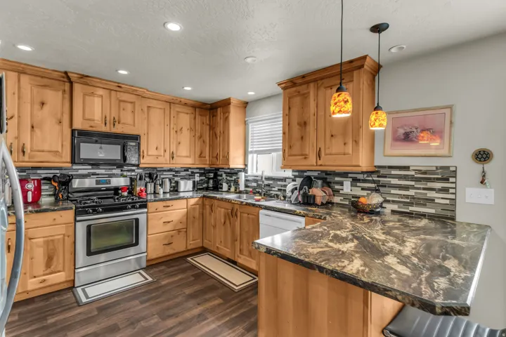 Kitchen featuring wood cabinetry, stainless steel appliances, dark wood-finish flooring, and a multi-toned tile backsplash
