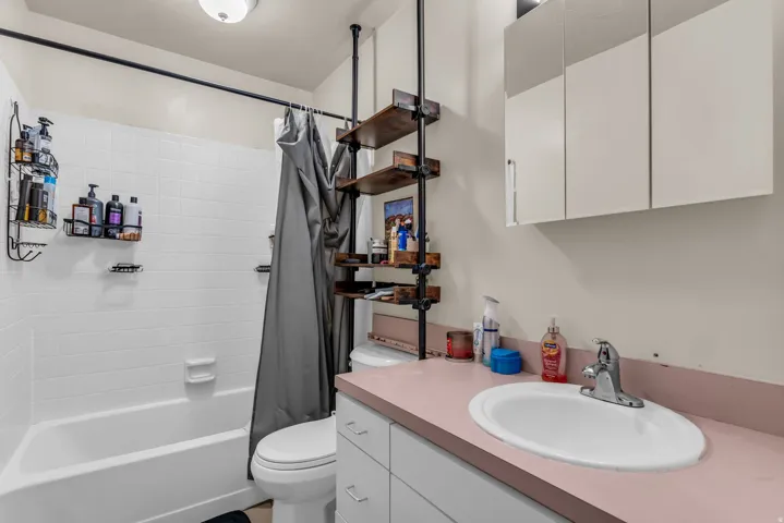 Bathroom featuring a white bathtub with subway tile surround, white toilet, and a vanity with a drop-in sink