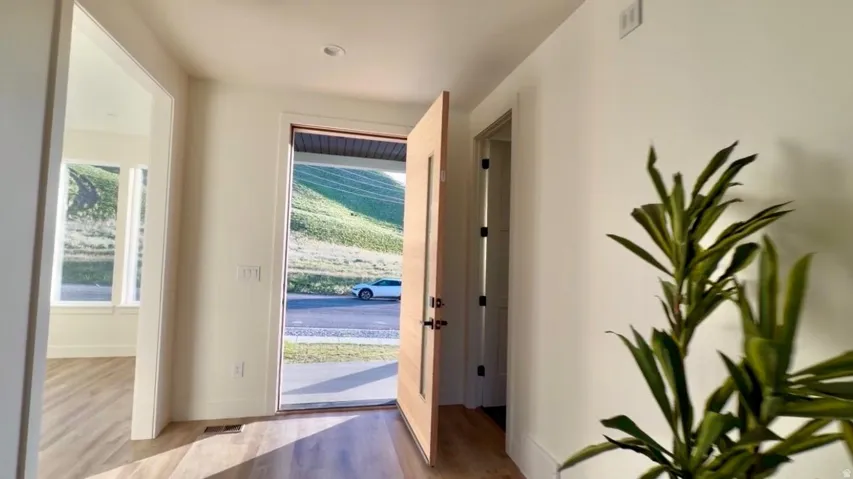 Entryway featuring light wood-finish flooring, recessed ceiling lighting, and a modern wooden door with frosted glass paneling