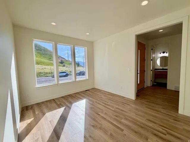 Room featuring wood-finish flooring, recessed lighting, and a trio of tall windows providing abundant natural light
