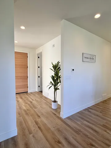 Entryway featuring wood-finish flooring, white baseboards, recessed lighting, and a paneled wood door