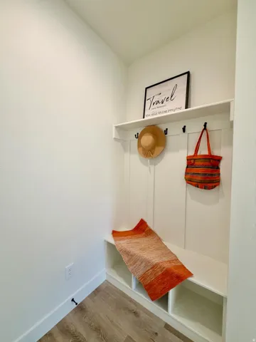 Built-in mudroom bench with three storage cubbies, four coat hooks, and an upper shelf