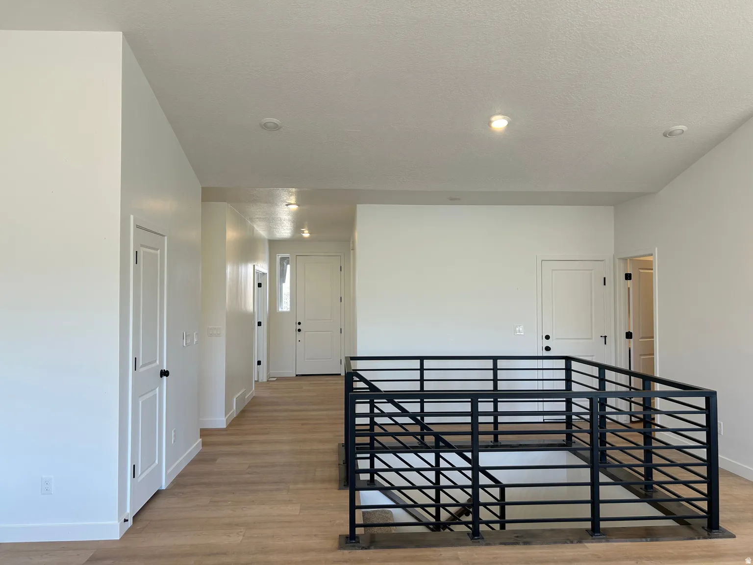 Open concept upper level featuring light wood-finish flooring and contemporary black metal railings