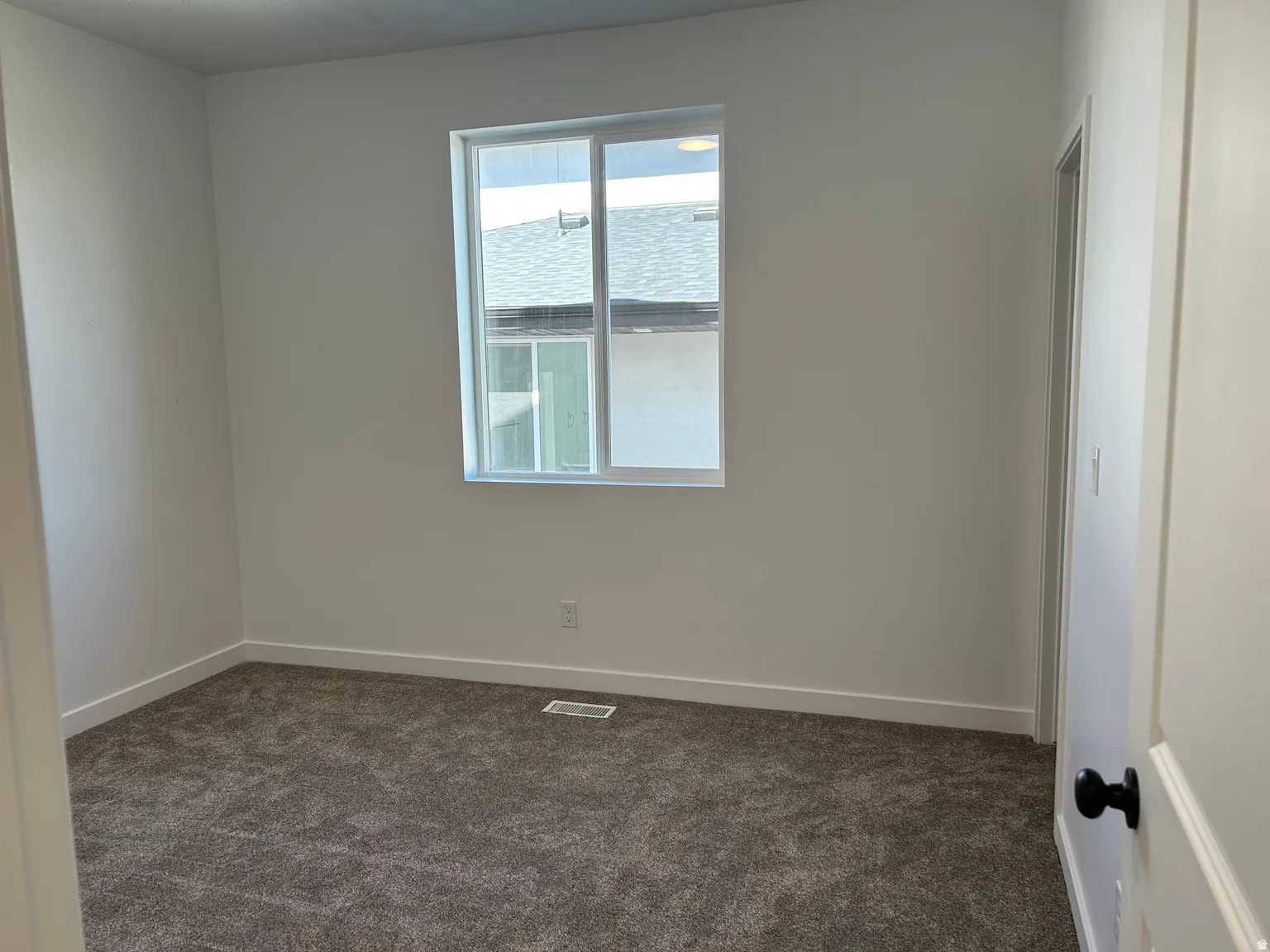 Room featuring neutral wall tones, white trim, and a window with a white frame