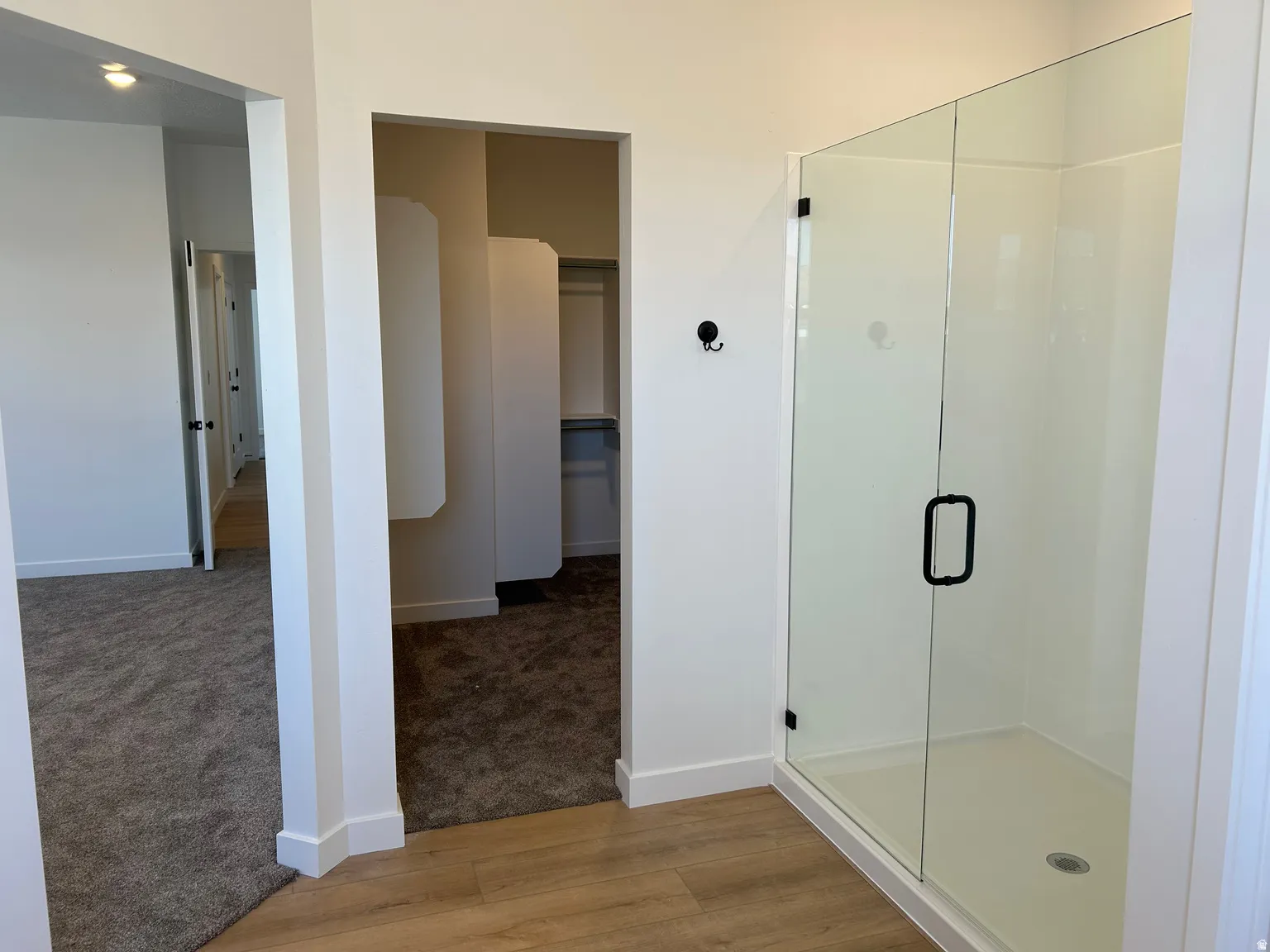 Shower enclosure with a clear glass door, matte black hardware, and a white base