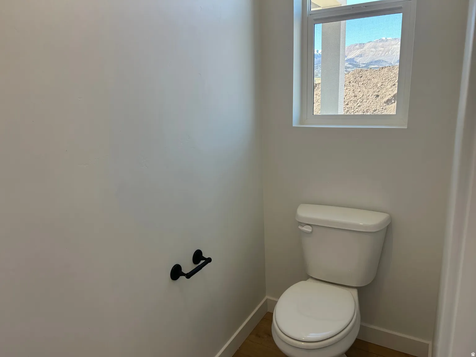 White toilet with a mountain backdrop visible through a rectangular window