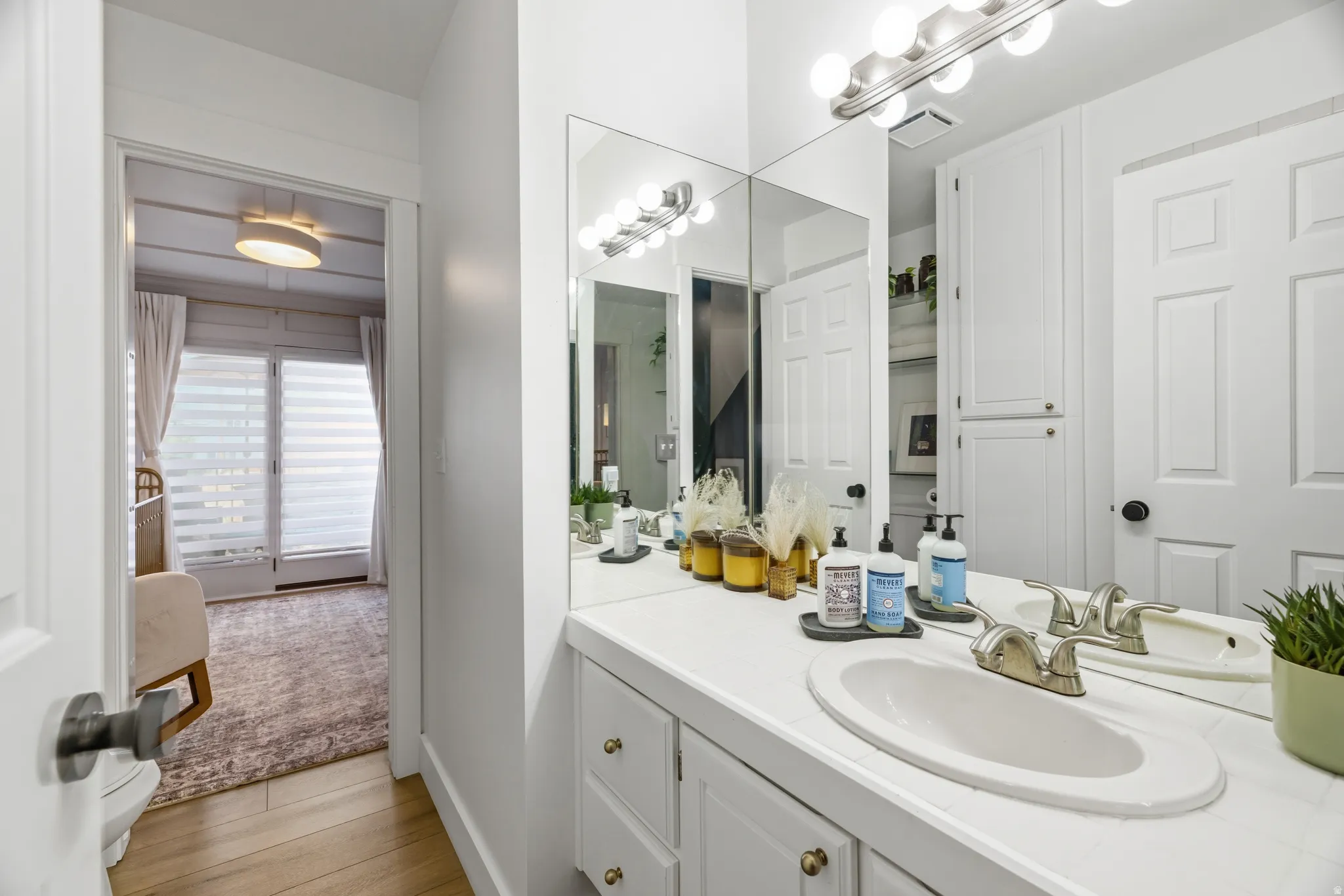 White vanity with integrated sink, dual-handle faucet, and brass-tone cabinet hardware