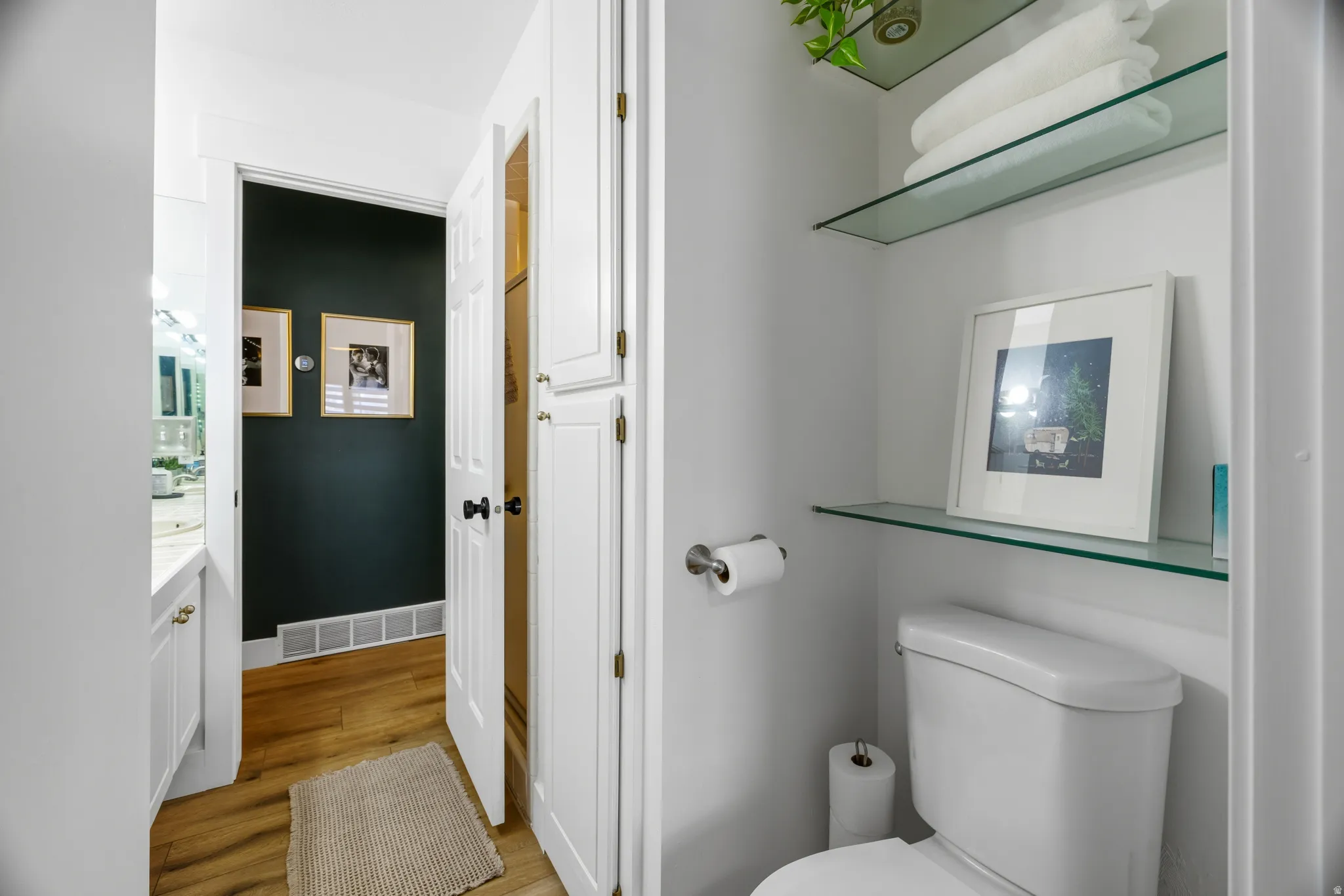 Hallway with wood-finish flooring, white cabinetry, and a dark accent wall