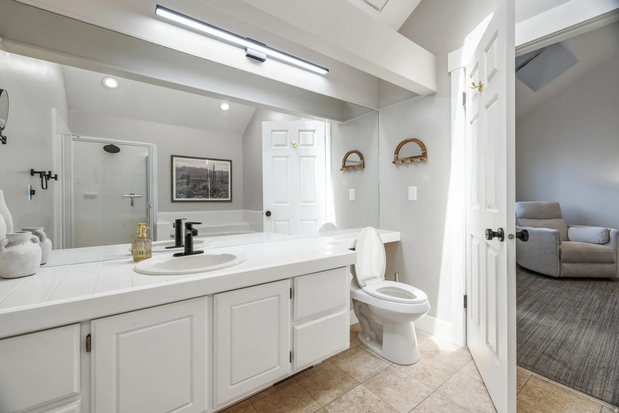 Bathroom featuring a white vanity with ample counter space, integrated sink, and matte black faucet