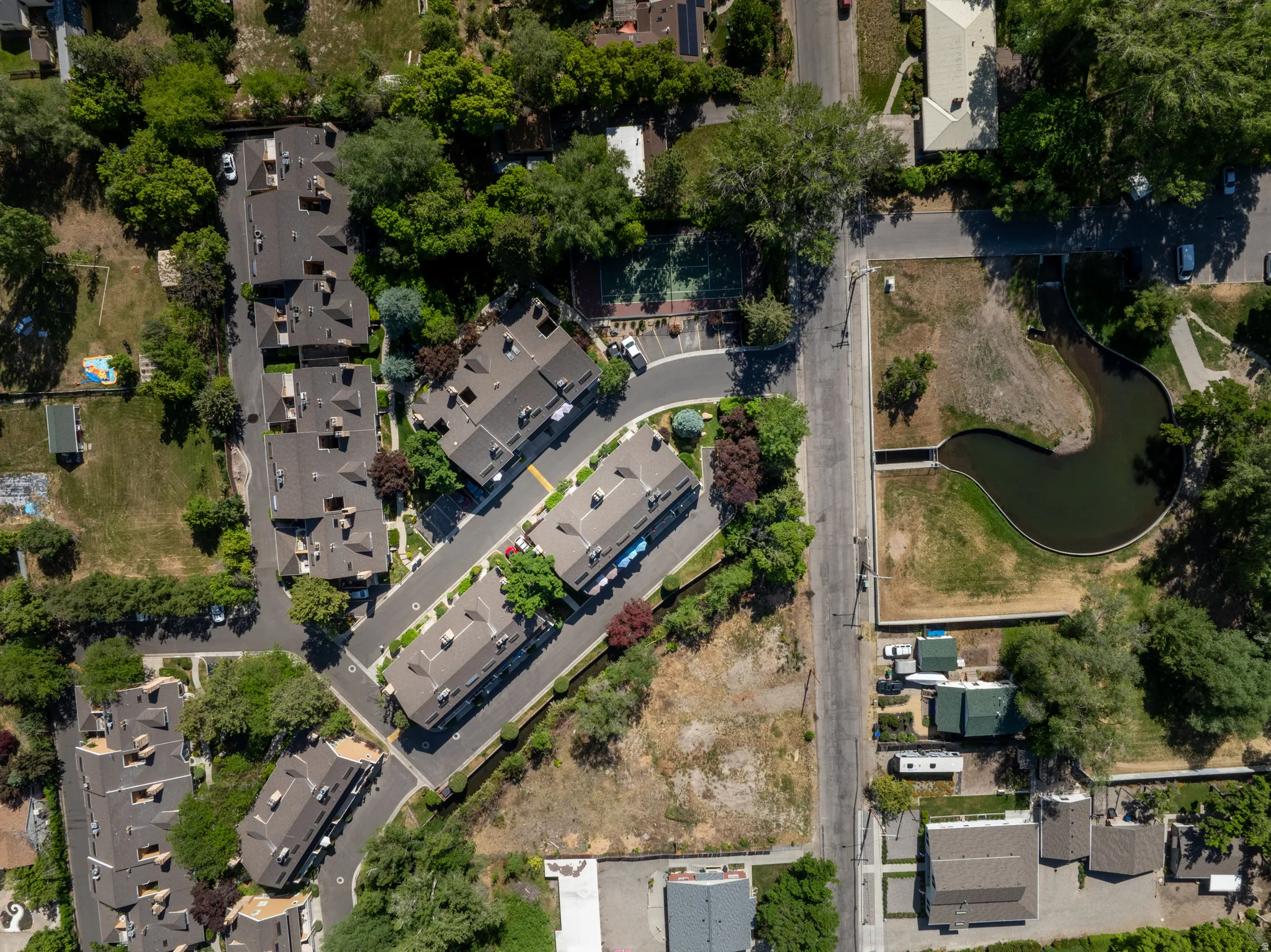 Aerial view showcasing multiple residential buildings with dark shingle roofing, surrounded by mature trees