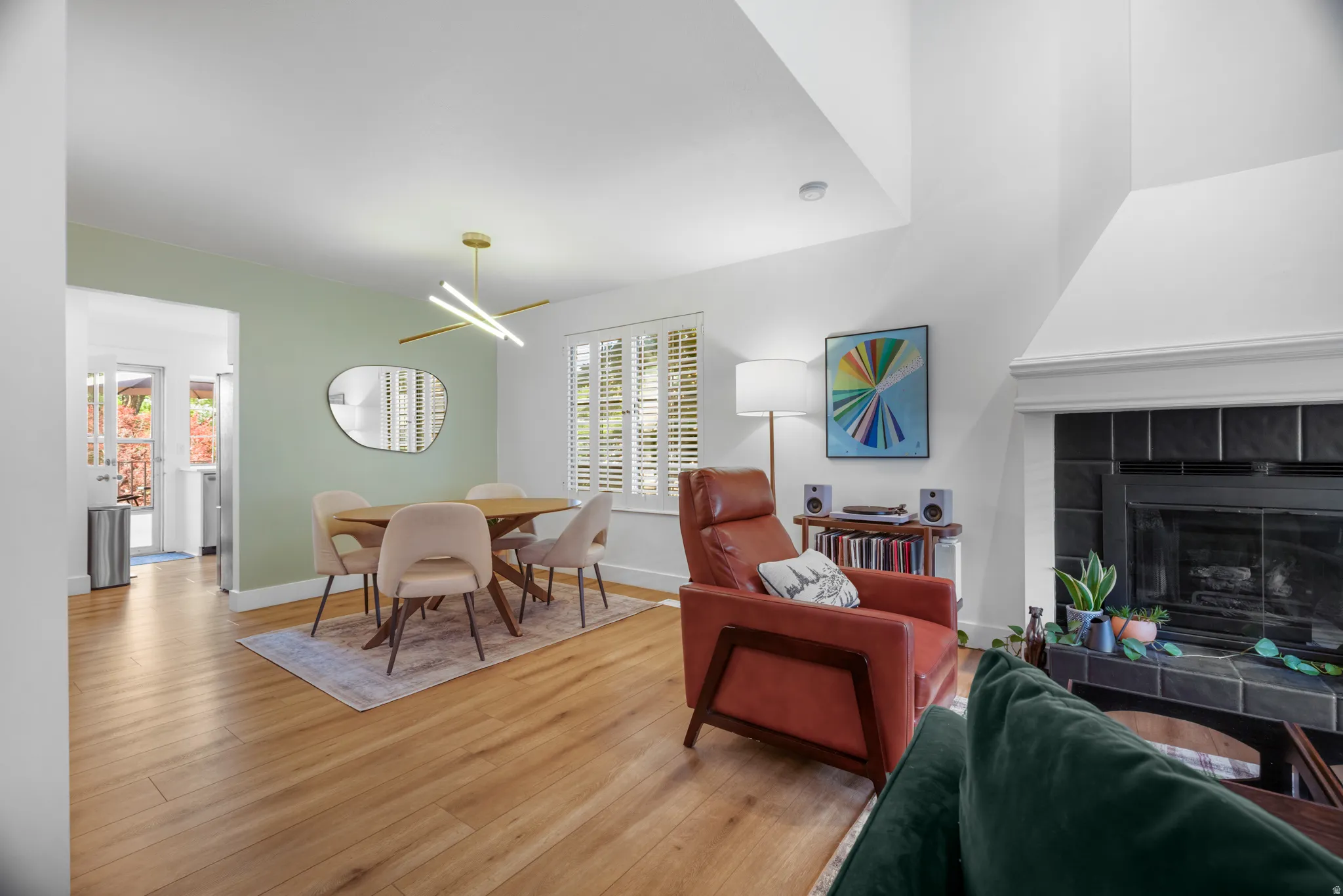 Open-concept living area featuring wood-finish flooring, a fireplace with dark tile surround, and vaulted ceilings