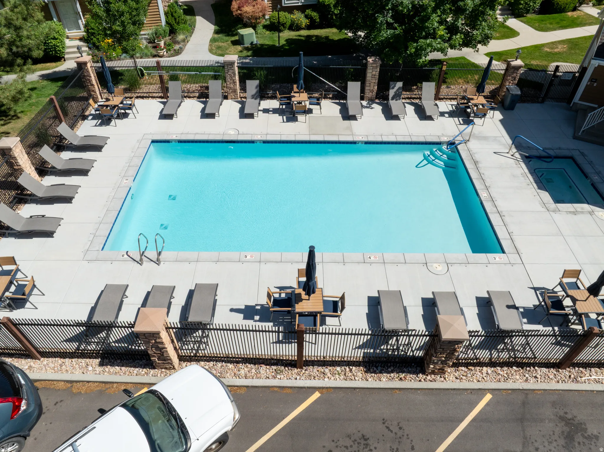 Resort-style pool area featuring a rectangular swimming pool, integrated spa, and extensive concrete decking