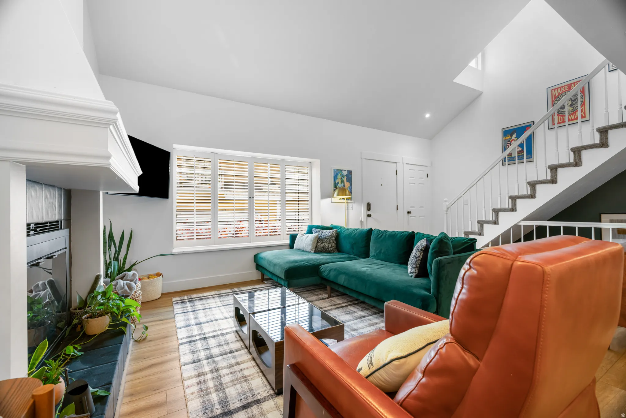 Living area featuring vaulted ceilings, wood-finish flooring, a contemporary fireplace with a sleek hearth, and window shutters