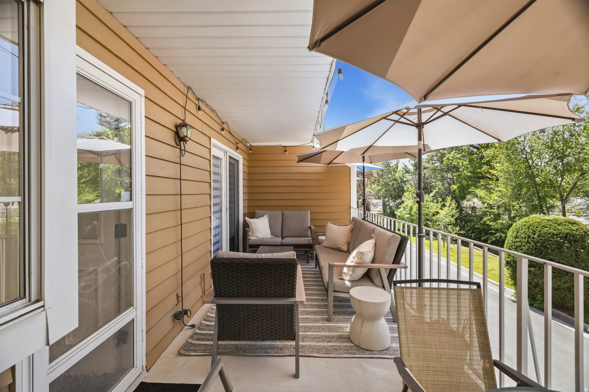 Expansive outdoor balcony featuring a neutral-toned privacy wall, white railing, and a sliding glass door entry