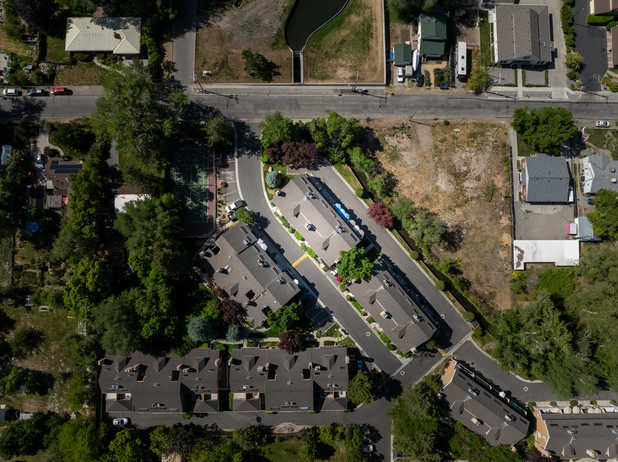 Aerial perspective showcasing a residential area with varied housing structures, mature trees, and paved roadways