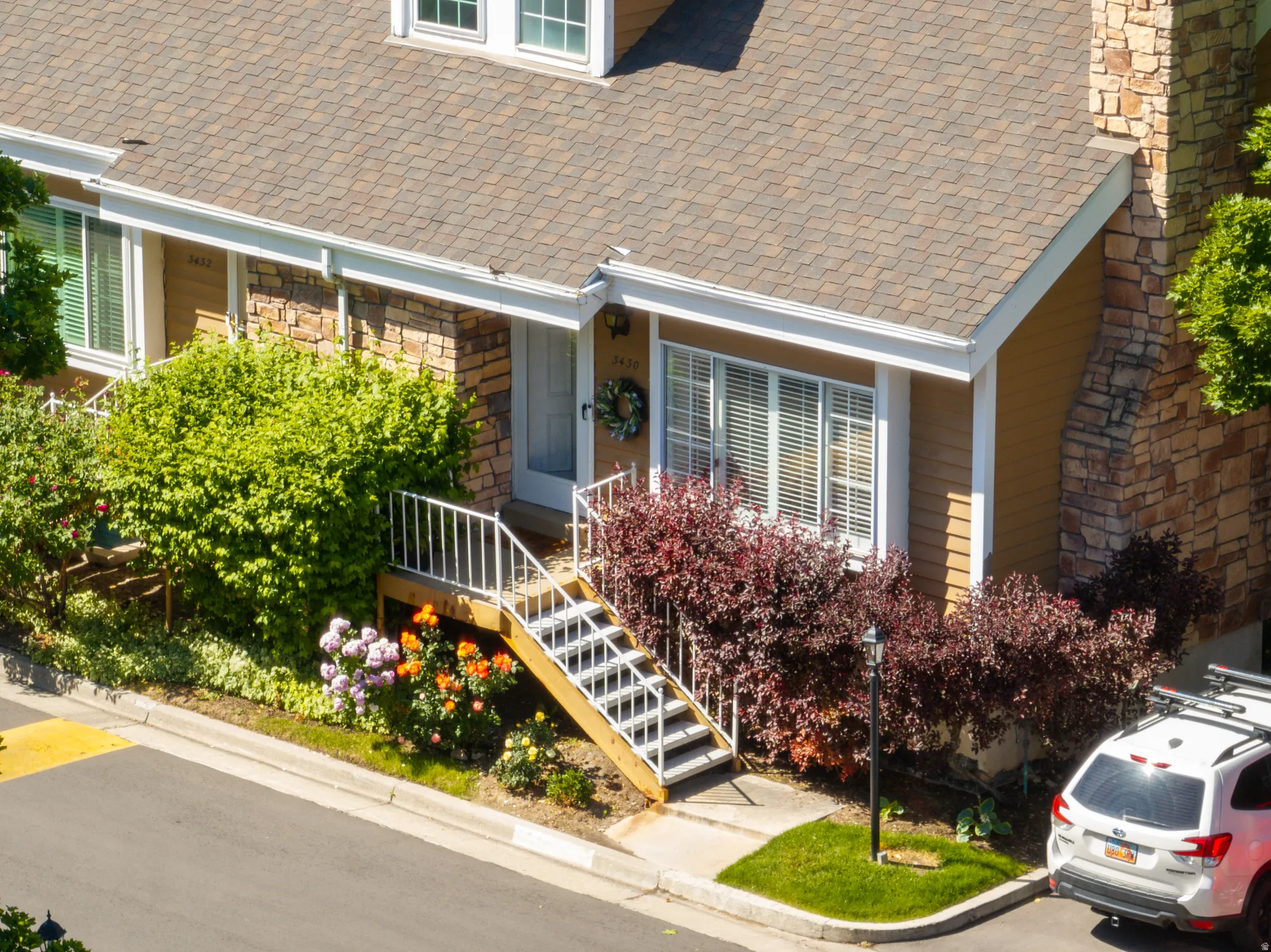 Multi-level residence featuring a prominent front staircase, stone veneer accents, and horizontal siding