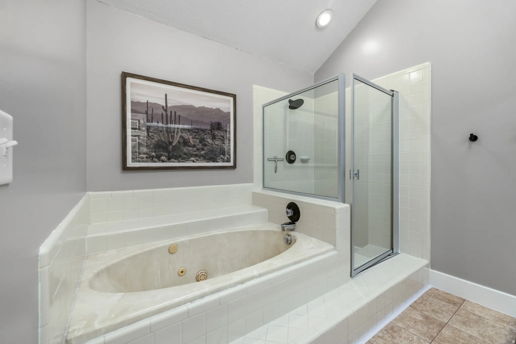 Soaking tub with integrated tile surround, glass-enclosed shower, and recessed ceiling lighting