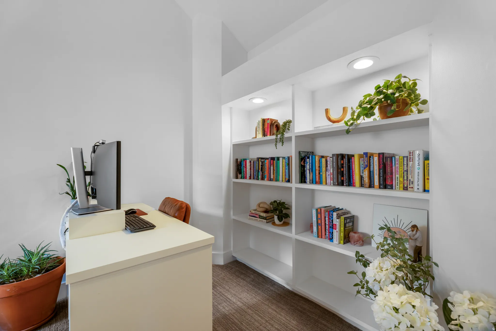 Built-in shelving with recessed lighting, integrated desk area, and wood-finish flooring