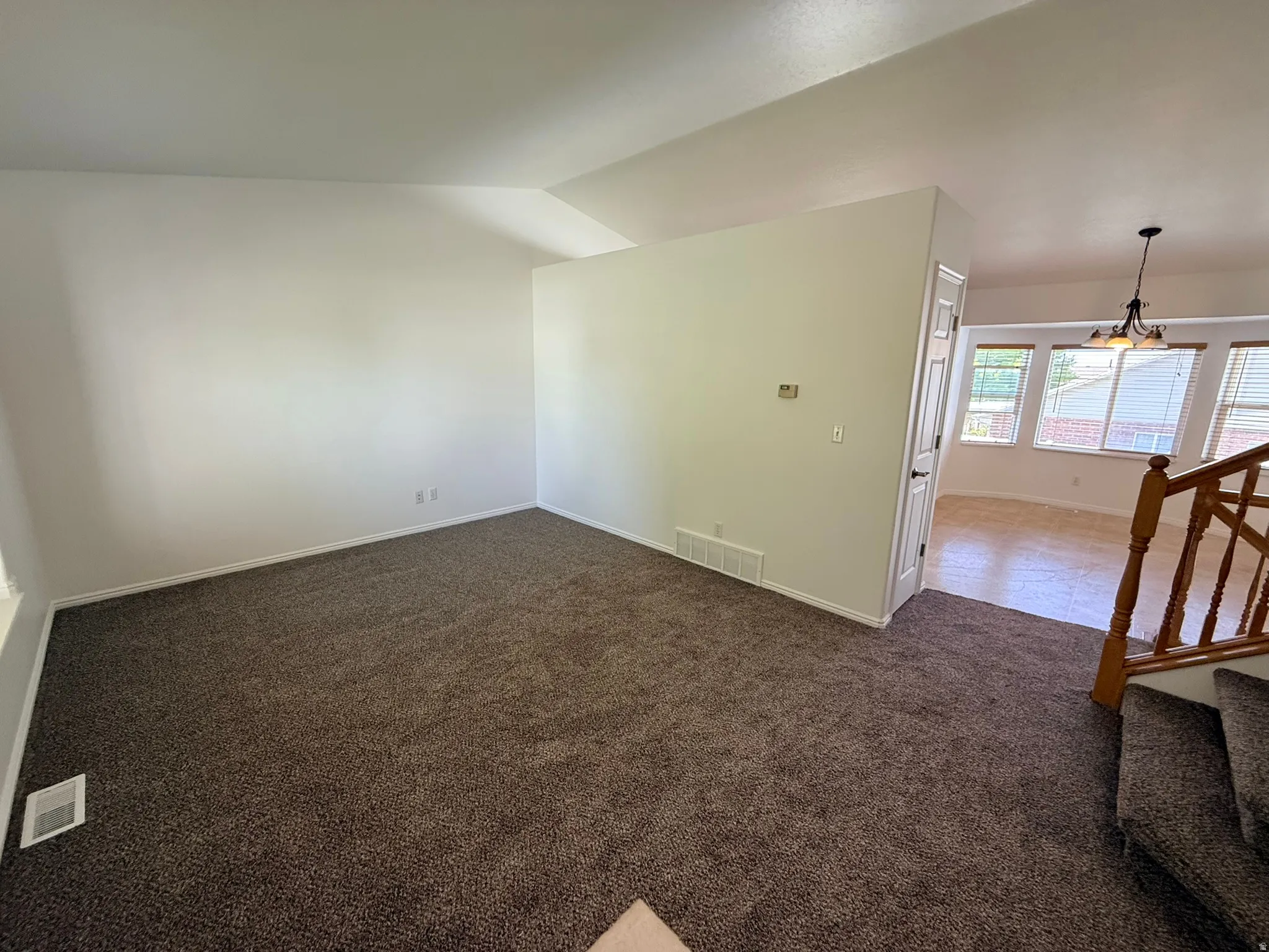 Spacious room featuring new brown carpet, white walls, and white baseboards