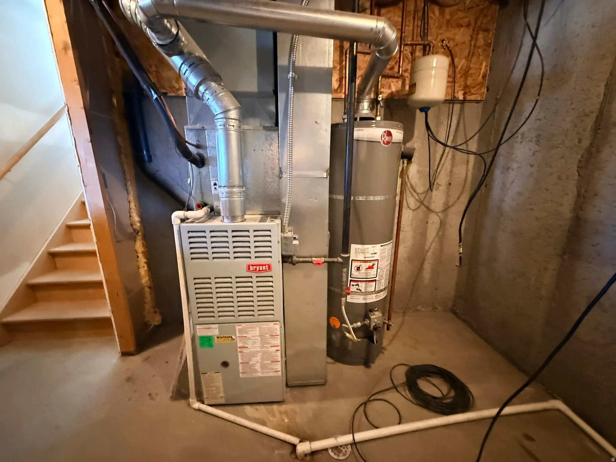 Utility area featuring a furnace, water heater, and unfinished wooden staircase