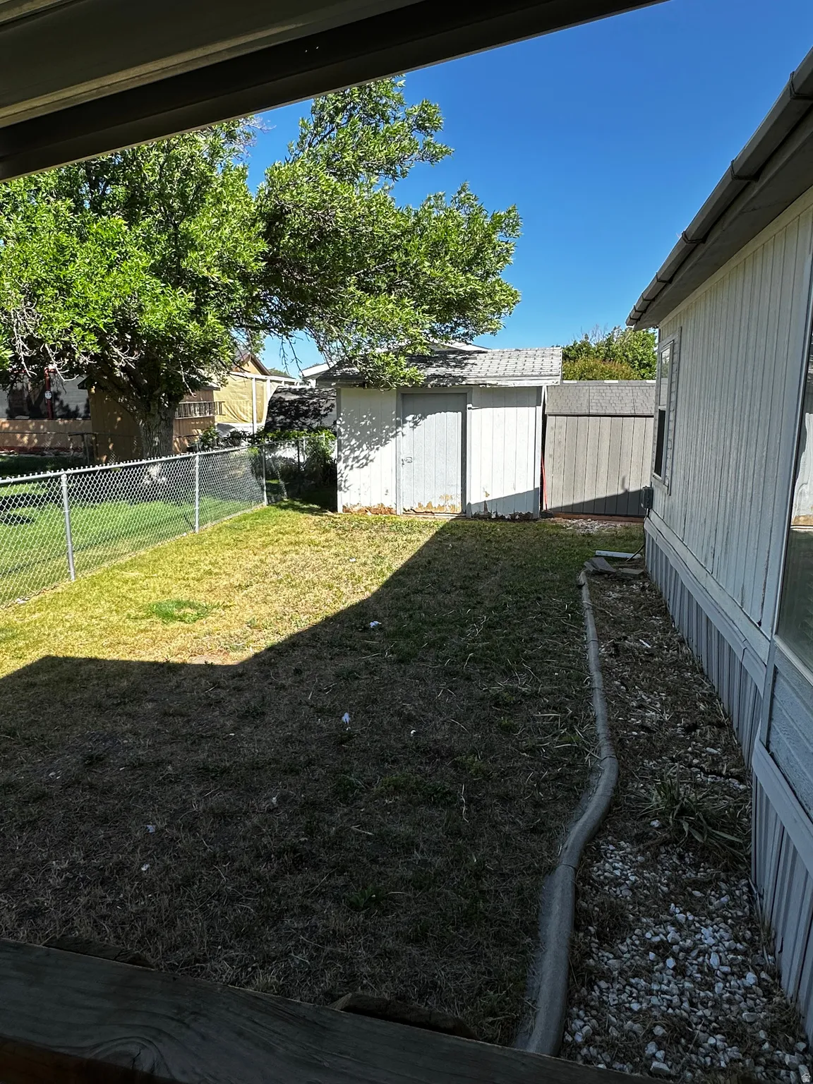Rear yard featuring a storage shed, chain link fencing, and a side garden area with concrete curbing