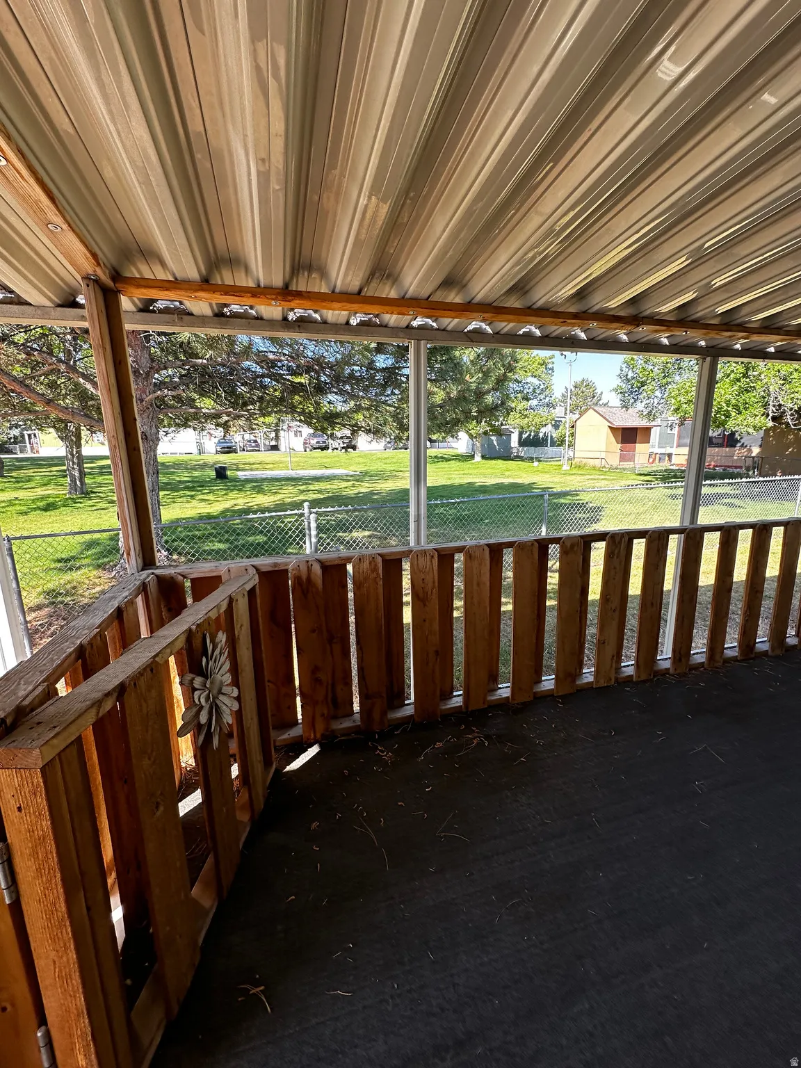 Covered patio space featuring a corrugated metal ceiling and wooden railing