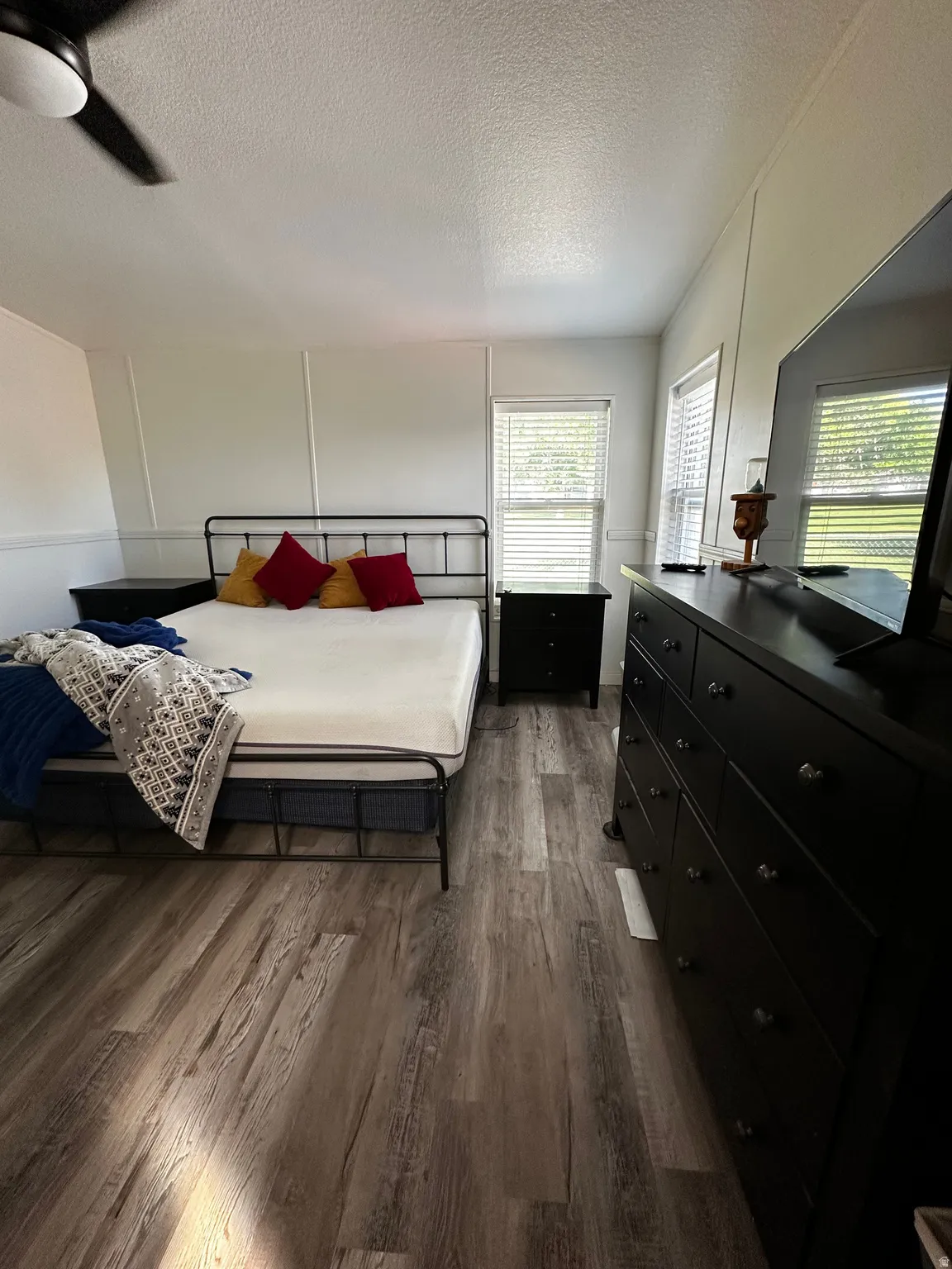 Spacious room featuring wood-finish flooring, white walls, and bright natural light from multiple windows