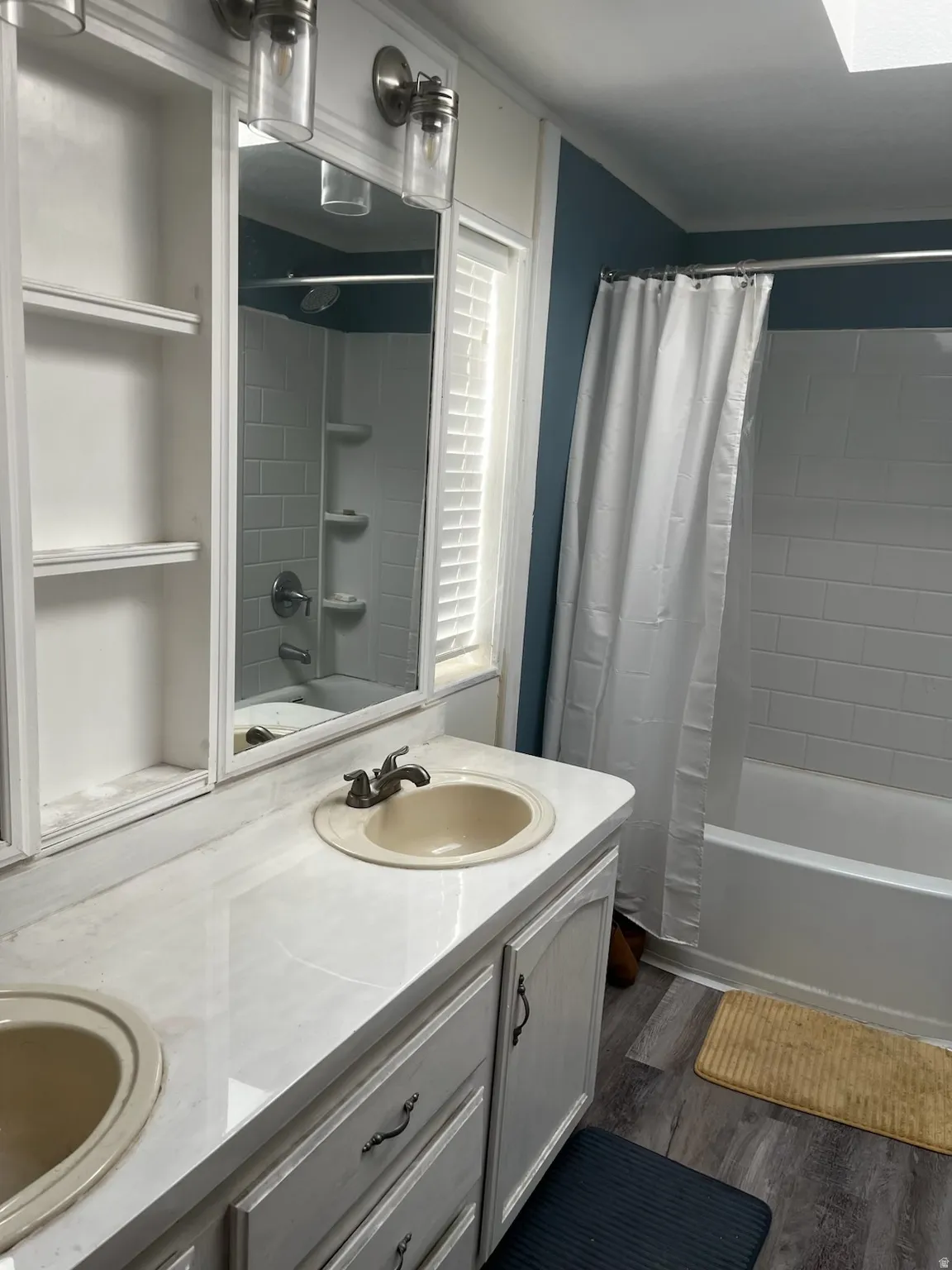 Double vanity with integrated sinks and brushed nickel faucets, featuring a built-in medicine cabinet with open shelving