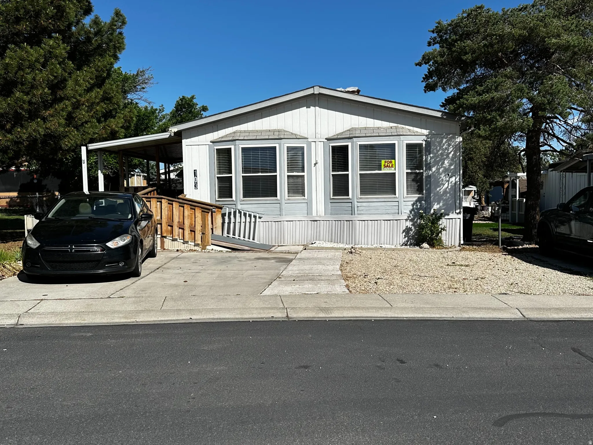 Single-story home featuring a covered carport, wood ramp access, and bay windows